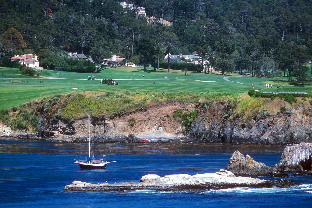 A sailboat rocks gently in a cove at Pebble Beach, California